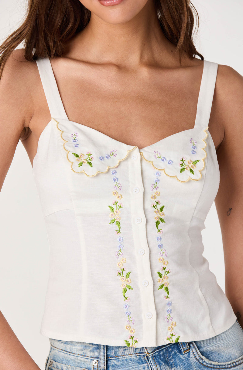 White sleeveless top with embroidered floral details and scalloped collar, button-front.