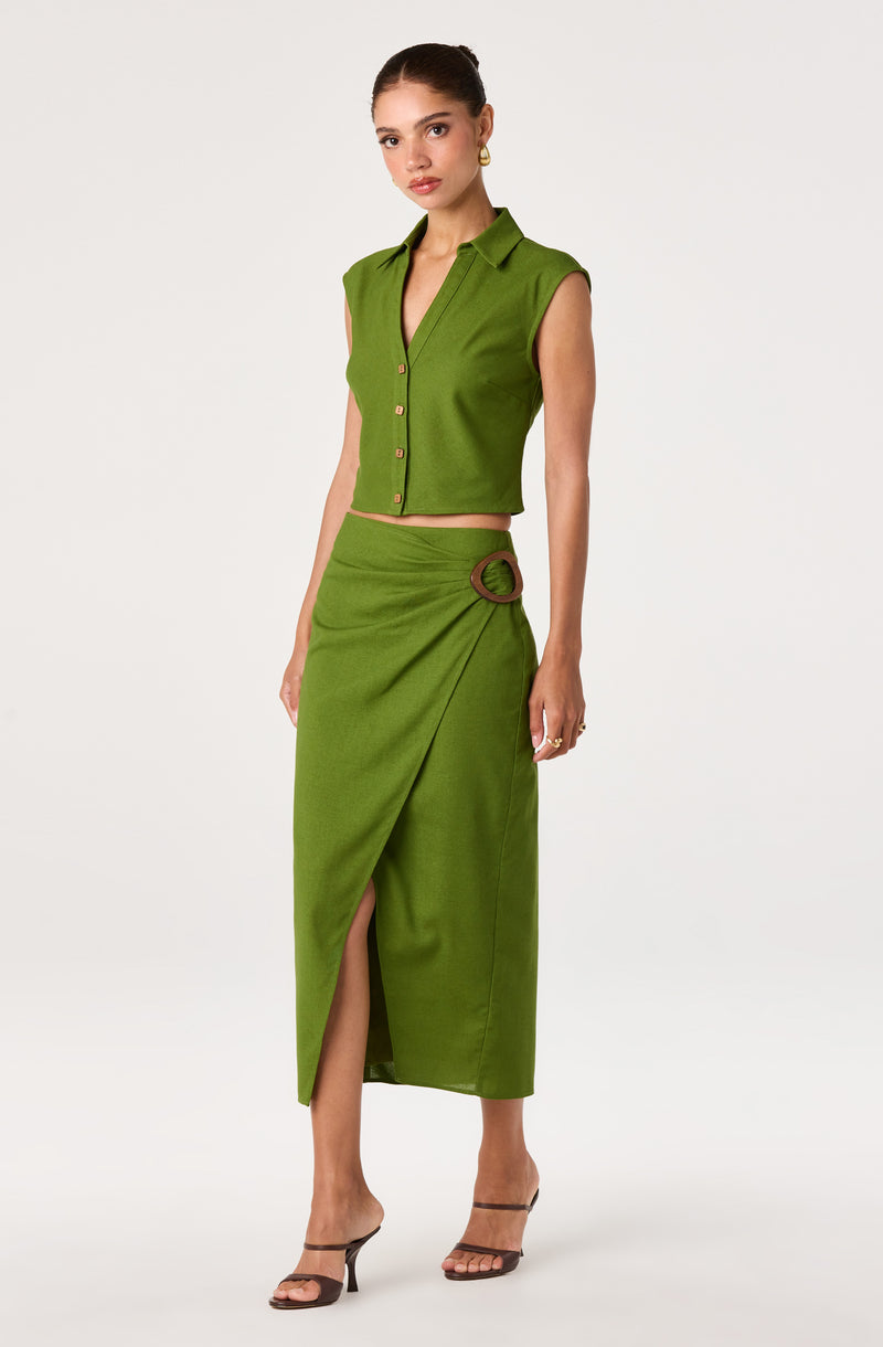 Woman wearing a sleeveless green button-up crop top and a matching green skirt with a side slit and circular buckle detail.
