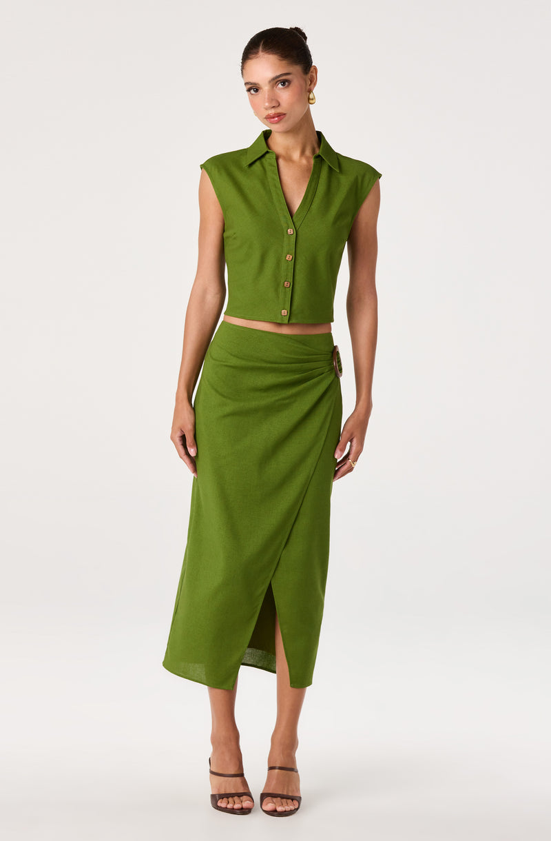 Woman wearing a sleeveless green button-up crop top and a matching green high-waisted skirt with a side slit and buckle detail.