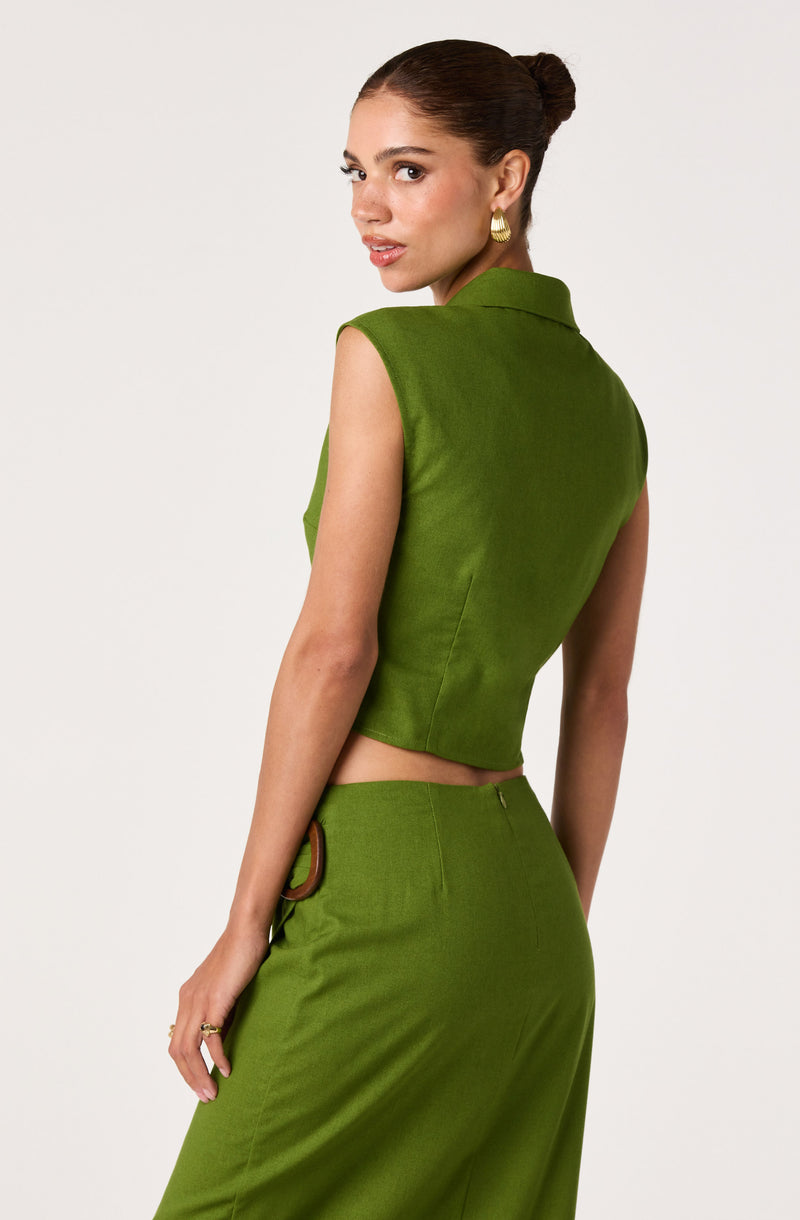 Woman wearing a sleeveless, collared green top and matching high-waisted green skirt.