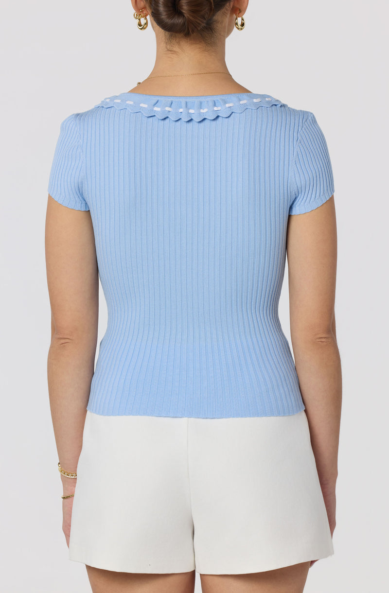 Light blue ribbed short-sleeve top with a scalloped collar and white shorts.