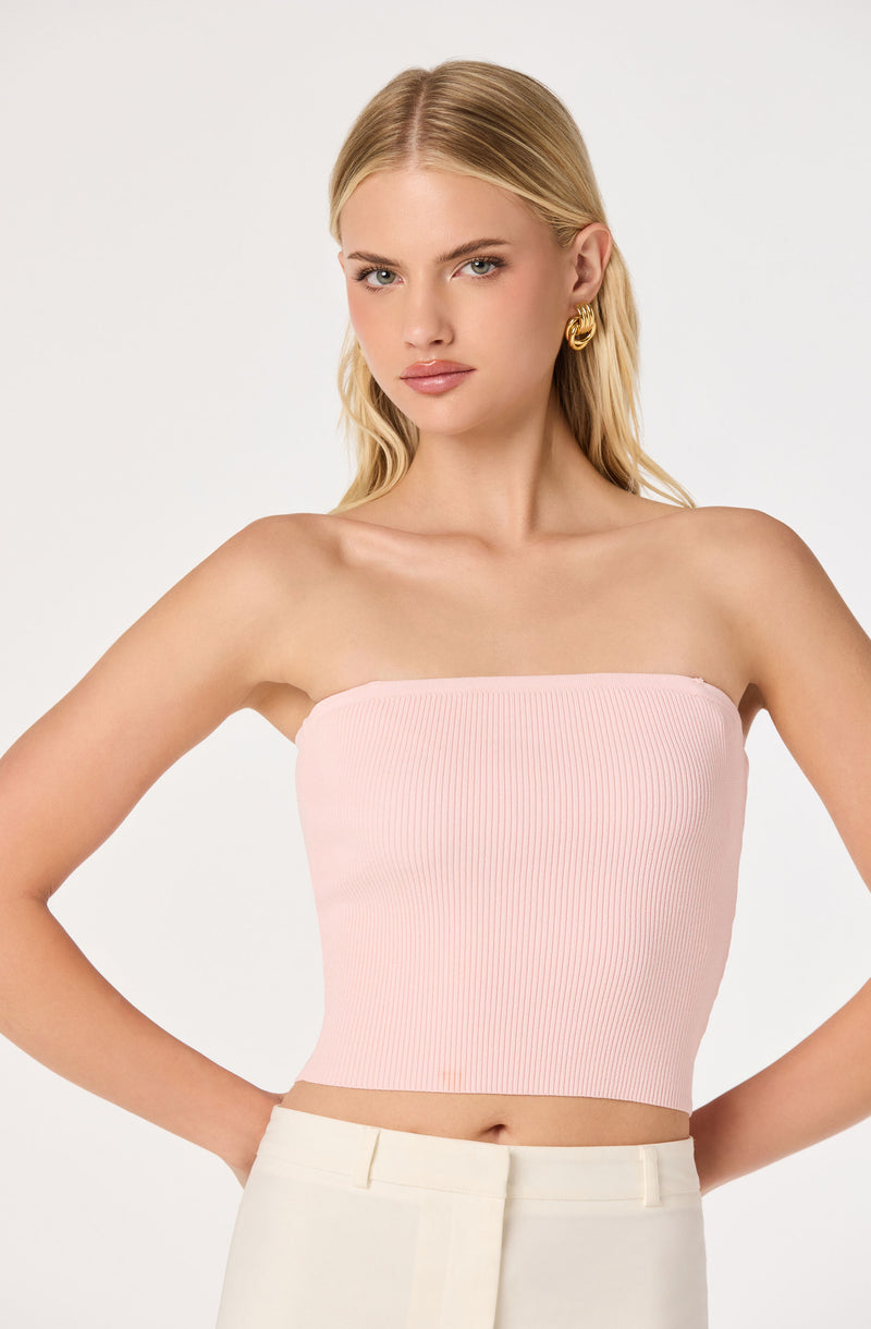 Pink ribbed strapless tube top, high-waisted beige pants.