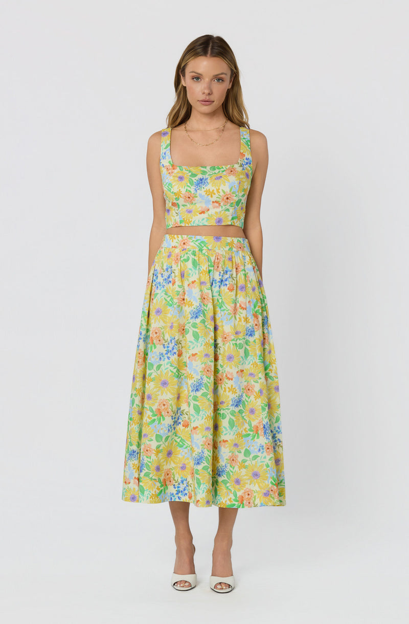 Woman wearing a two-piece floral crop top and matching long skirt.
