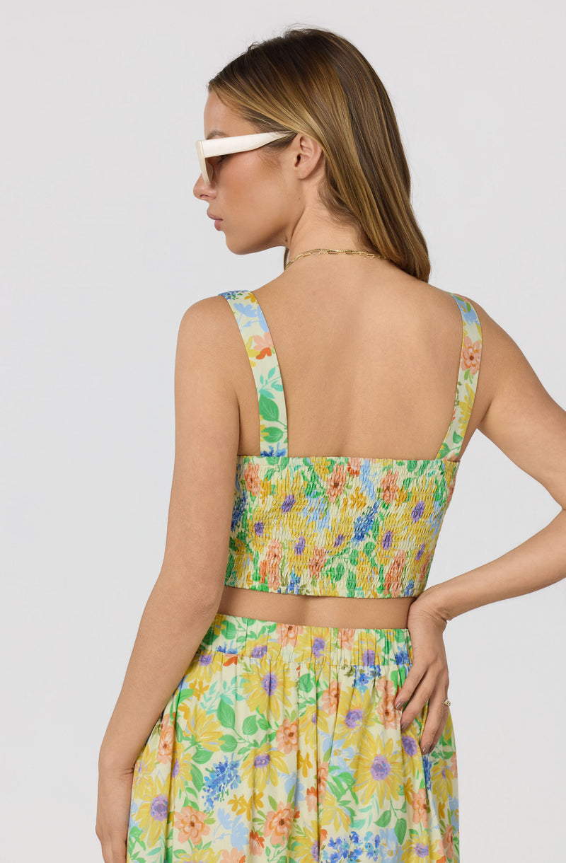 Woman wearing a colorful floral crop top and matching skirt, braided straps.