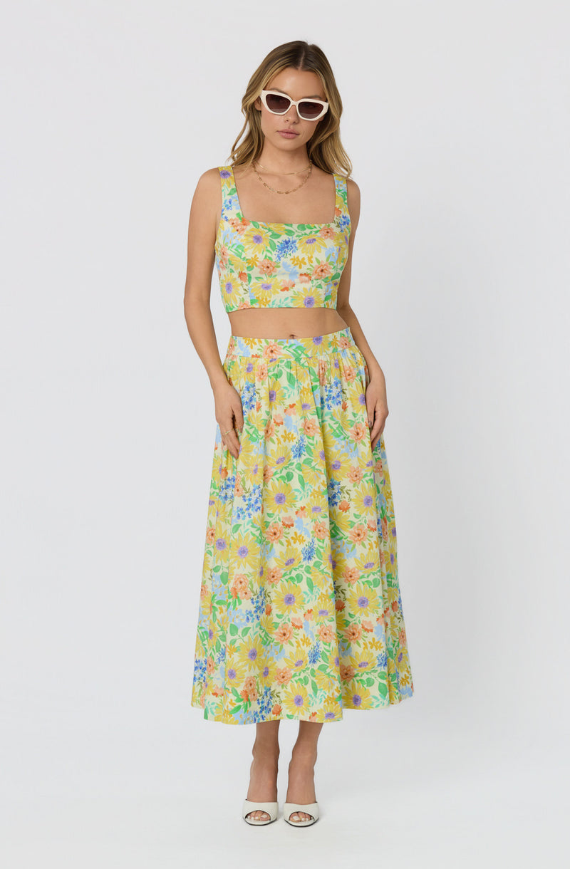 Woman wearing a matching floral crop top and wide-leg pants, with white sunglasses.