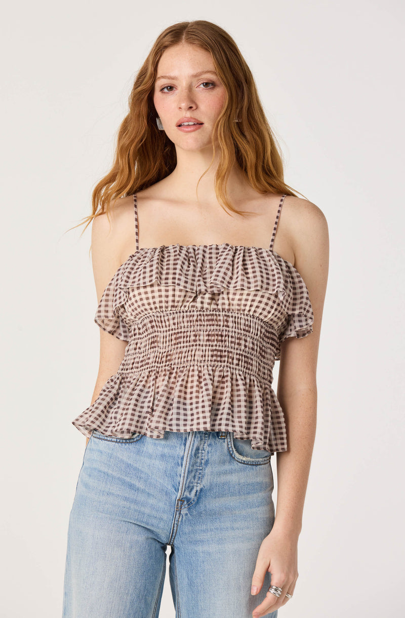 Woman wearing a brown and white checkered spaghetti strap top with ruffles and elastic waist.