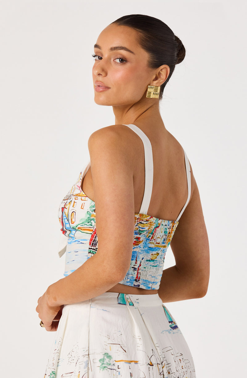 Woman wearing a colorful, patterned crop top with white shoulder straps and matching skirt.