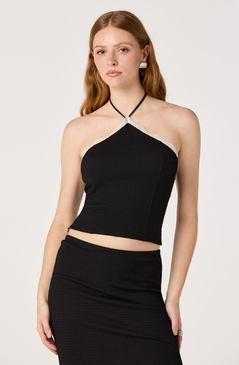 Black sleeveless halter top with white lace trim and matching black skirt.