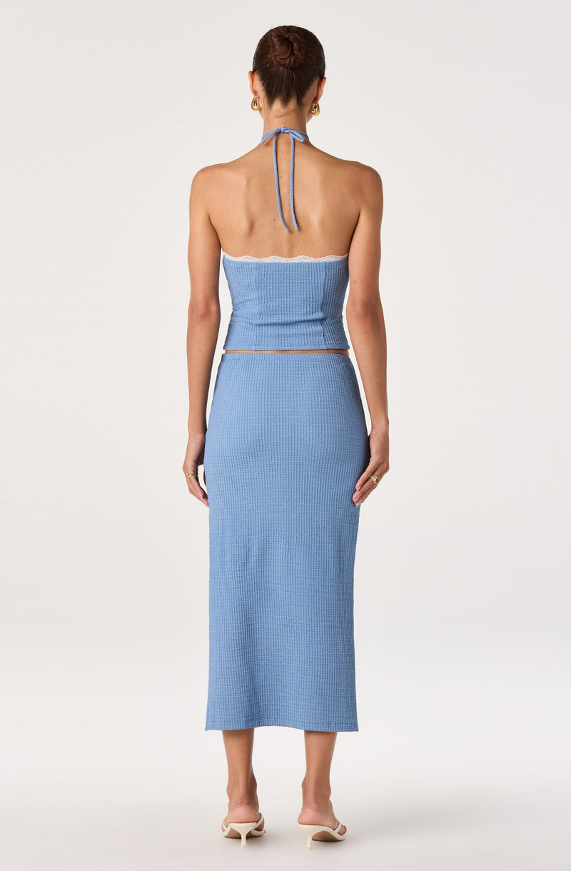 Woman in a two-piece light blue knit outfit, halter top and long skirt.