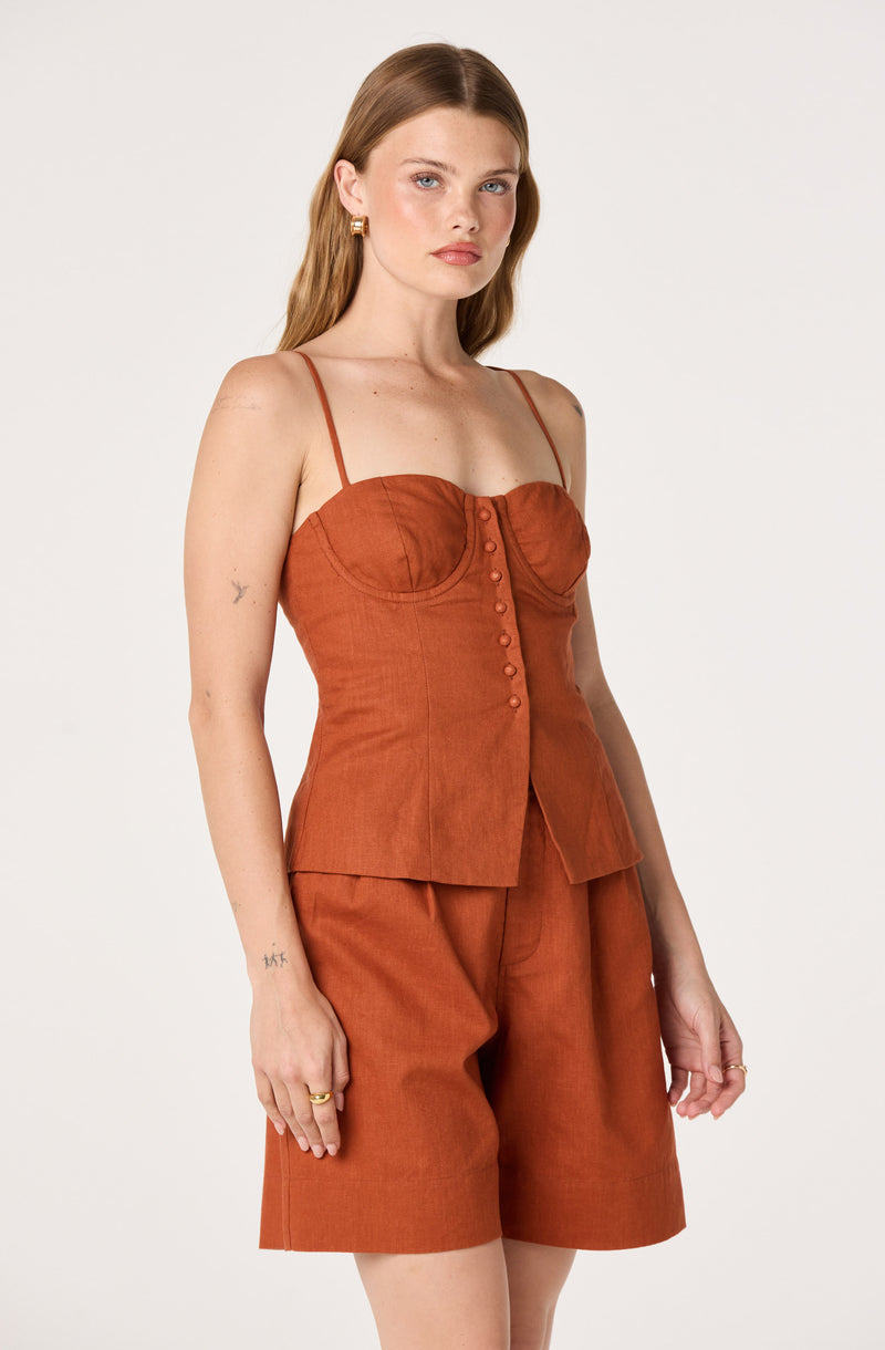 Woman wearing rust-colored sleeveless top with spaghetti straps and matching shorts.
