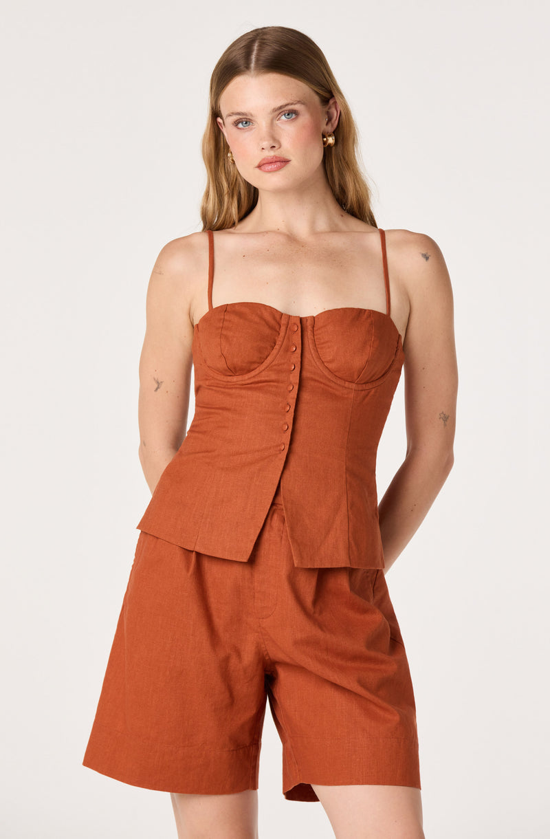 Woman in rust-colored sleeveless top with spaghetti straps and matching shorts.