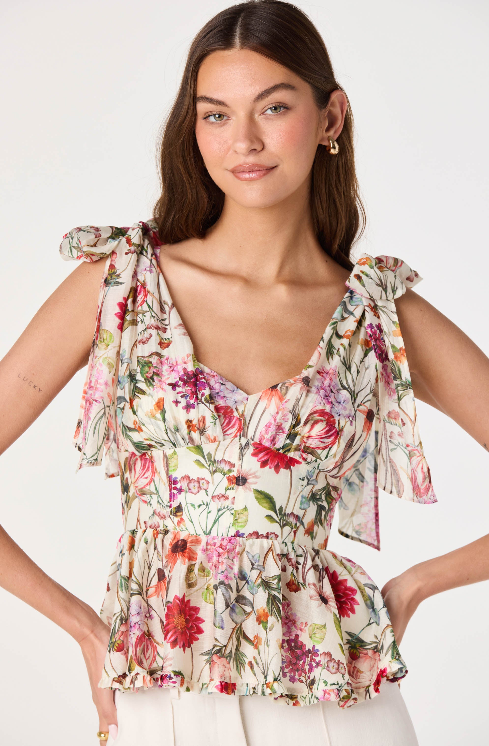 Sleeveless floral top with ruffled shoulder ties and a peplum hem.