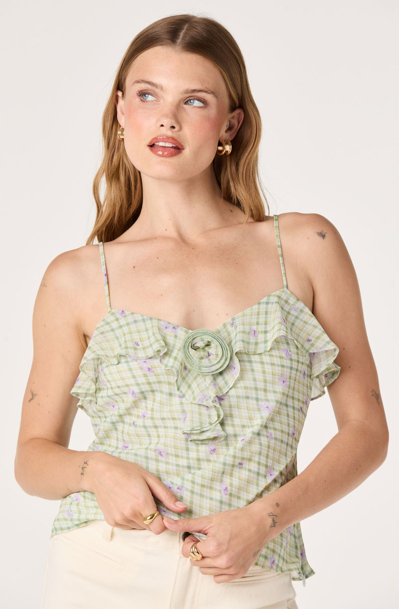 Woman wearing a green and purple checkered ruffled tank top with spaghetti straps.