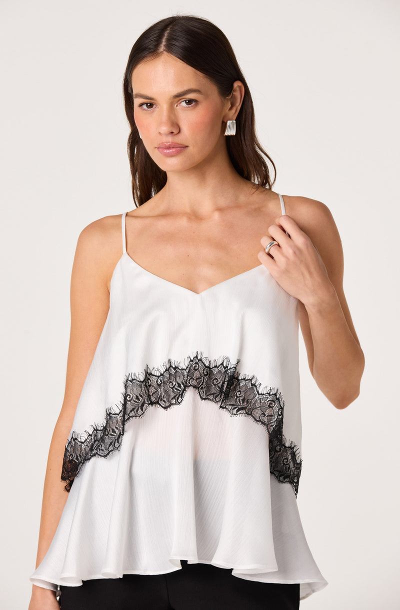 Woman in white satin top with black lace trim and spaghetti straps.