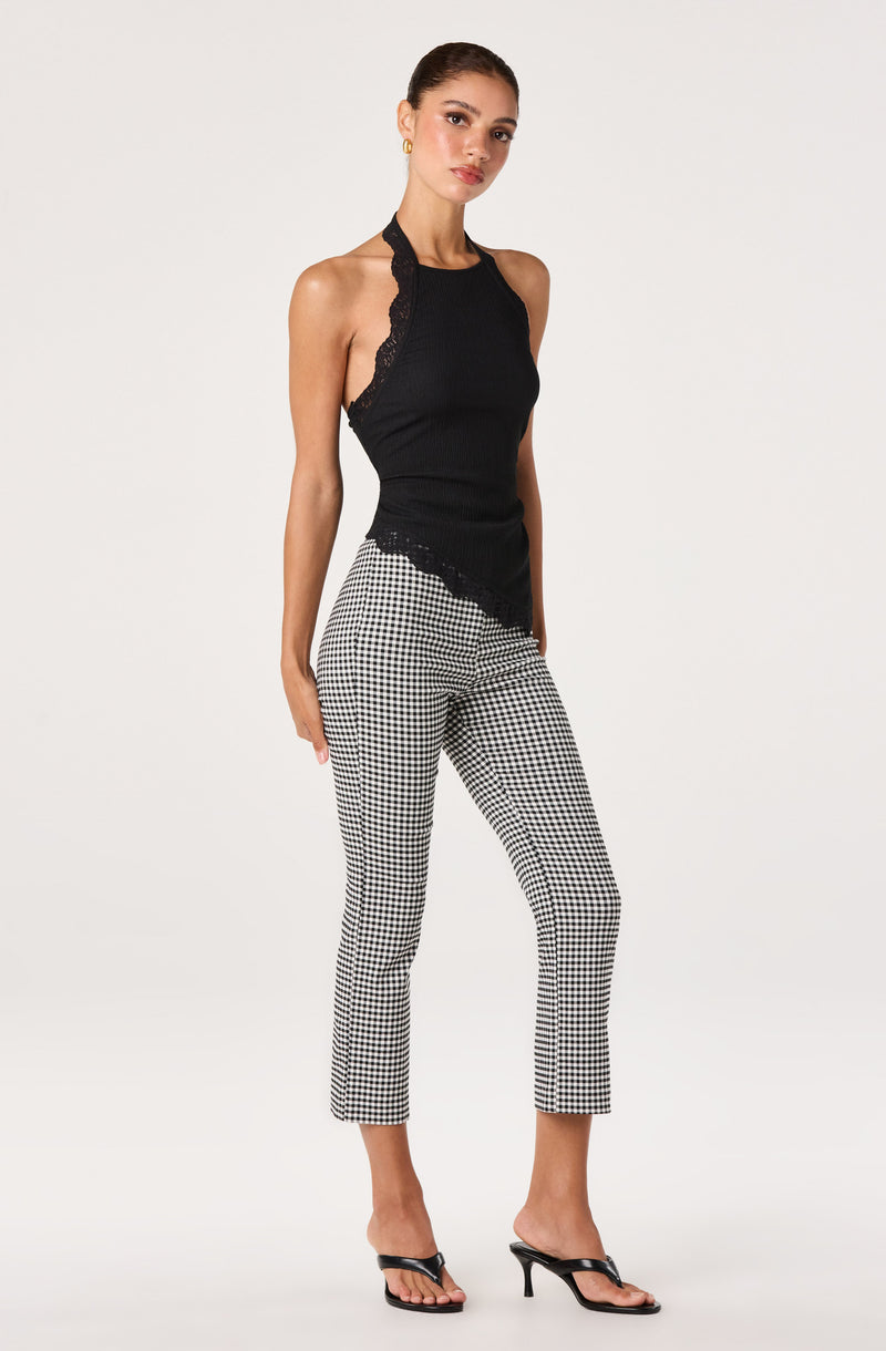 Woman wearing a black sleeveless lace trim top and black-and-white checkered cropped pants.
