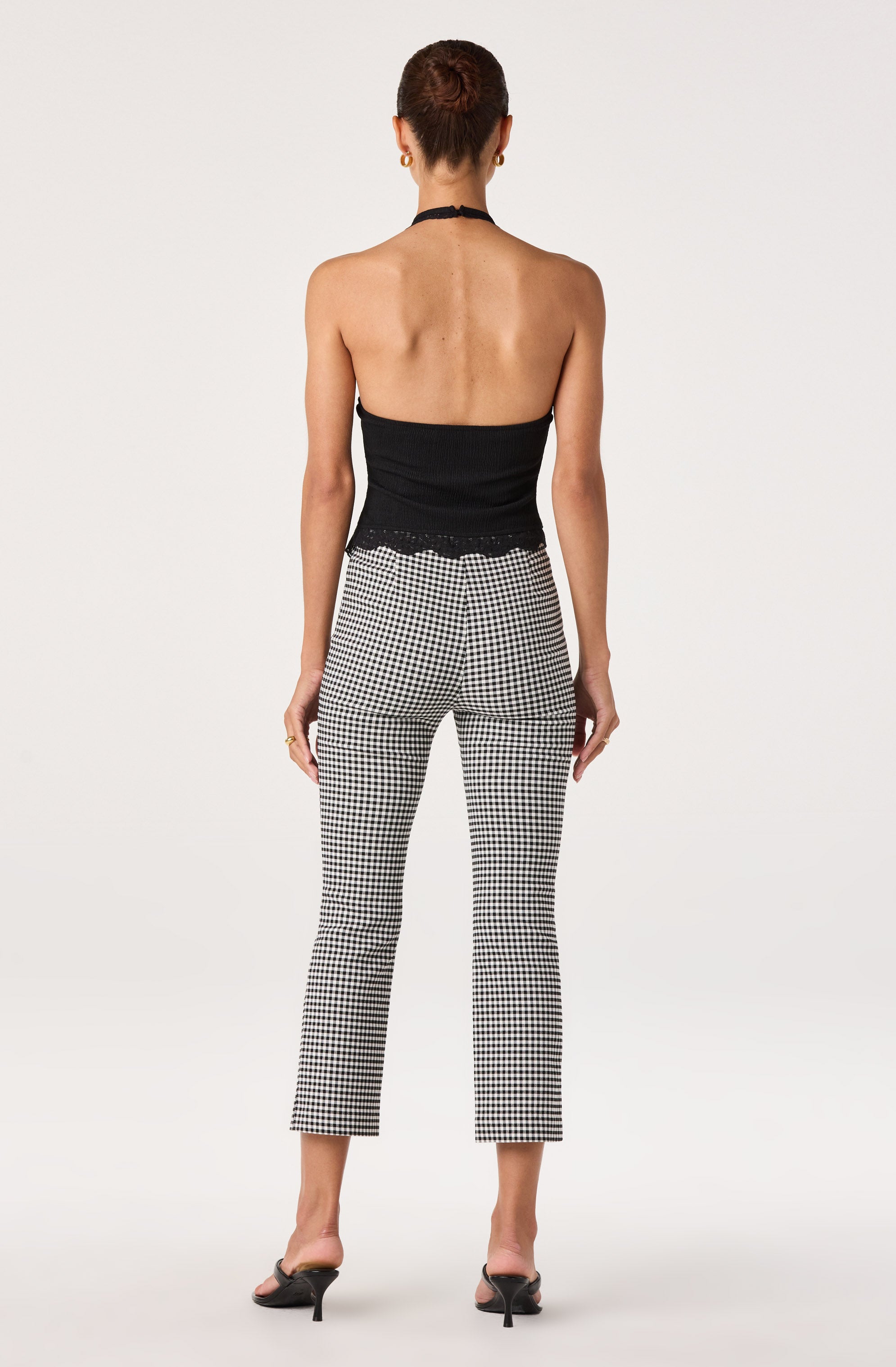 Back view of woman wearing a black halter top and black-and-white checkered pants with heels.