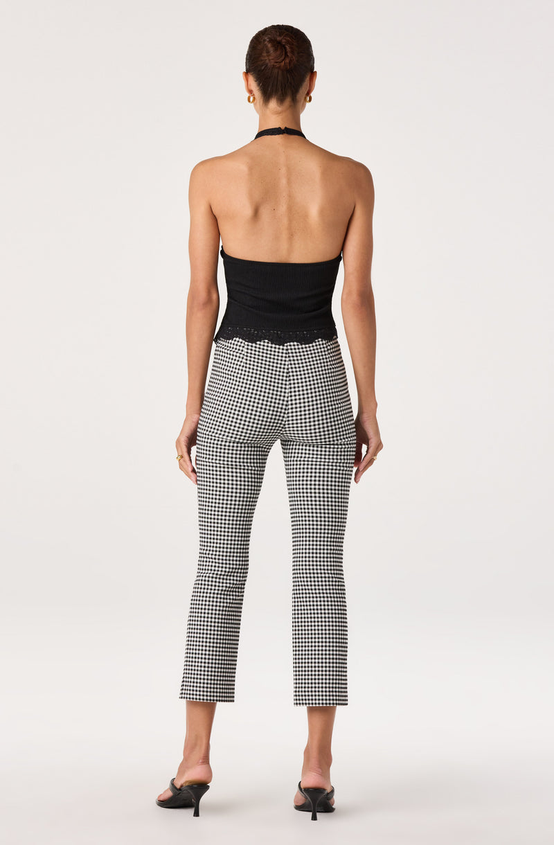 Back view of woman wearing a black halter top and black-and-white checkered pants with heels.