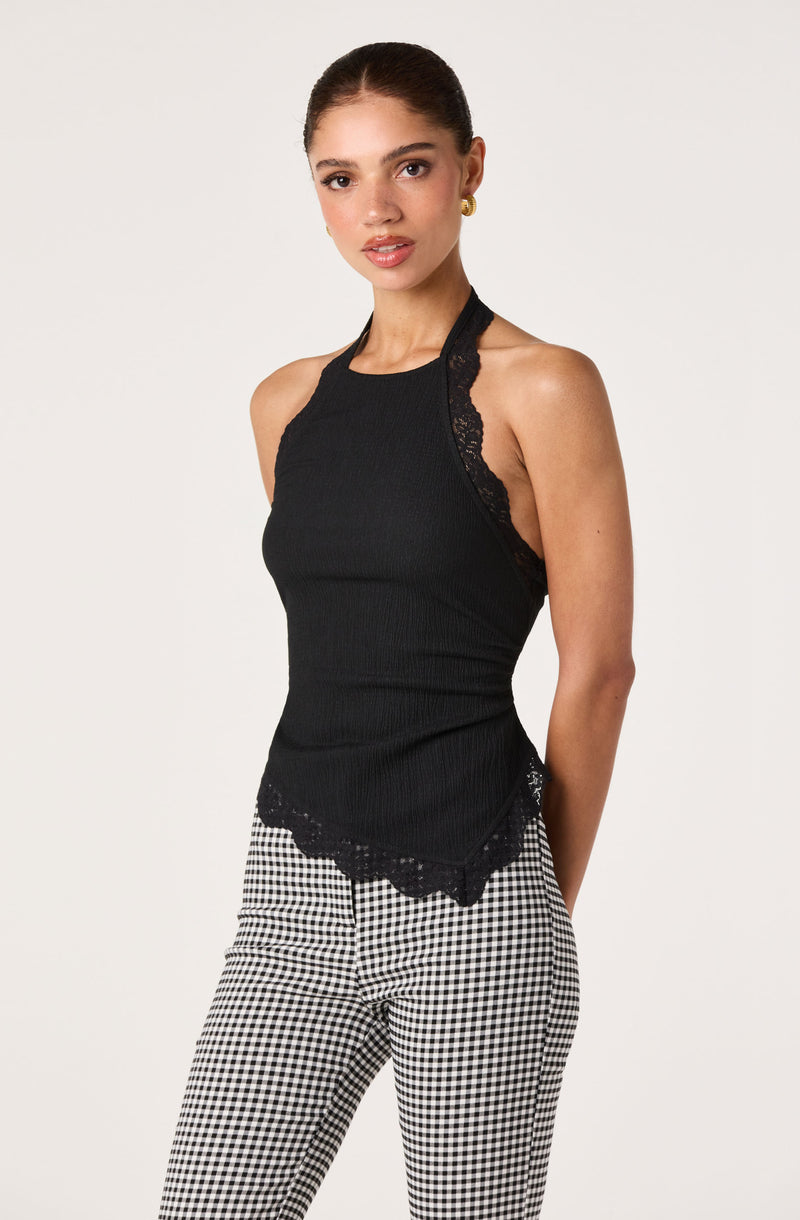 Woman wearing a black sleeveless top with lace detail and black-and-white checkered pants.