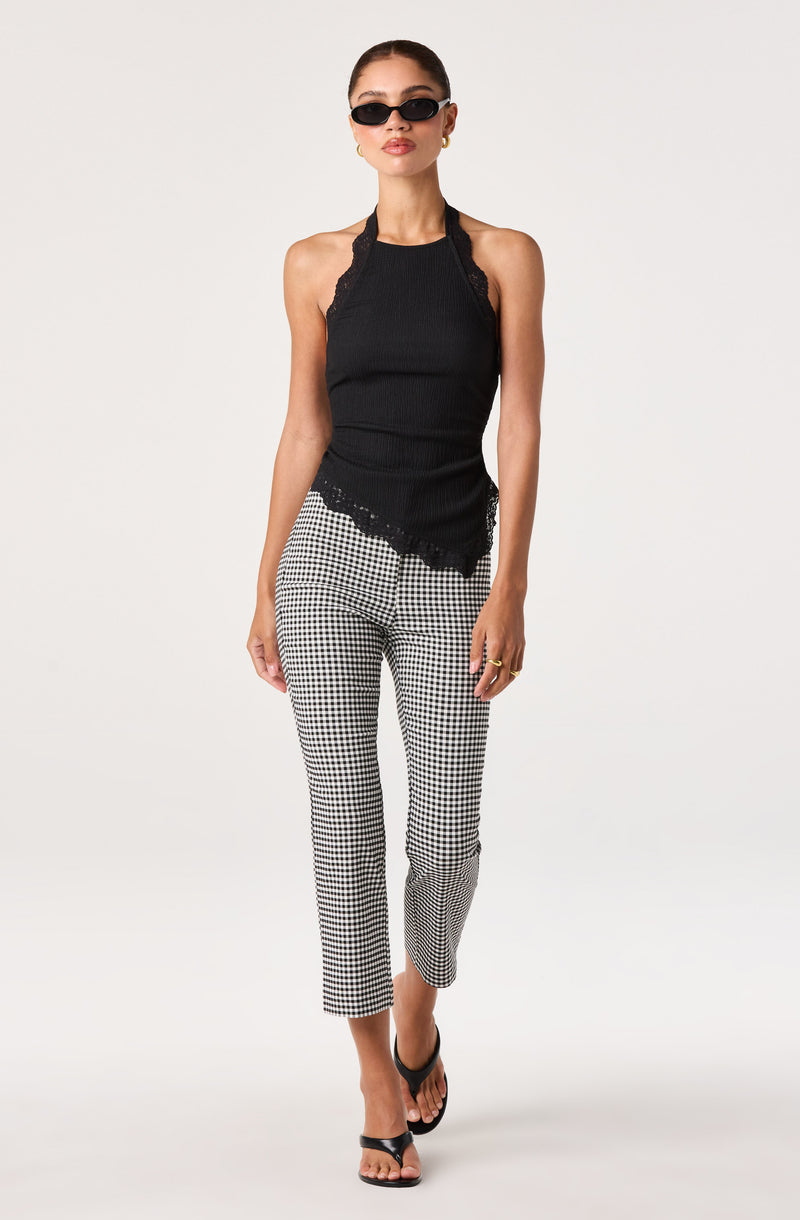 Woman wearing a black sleeveless top with lace details and checkered black-and-white pants.