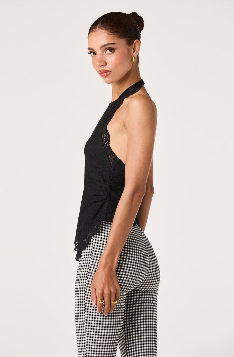 Woman wearing a black sleeveless top with lace details and black-and-white checkered pants.