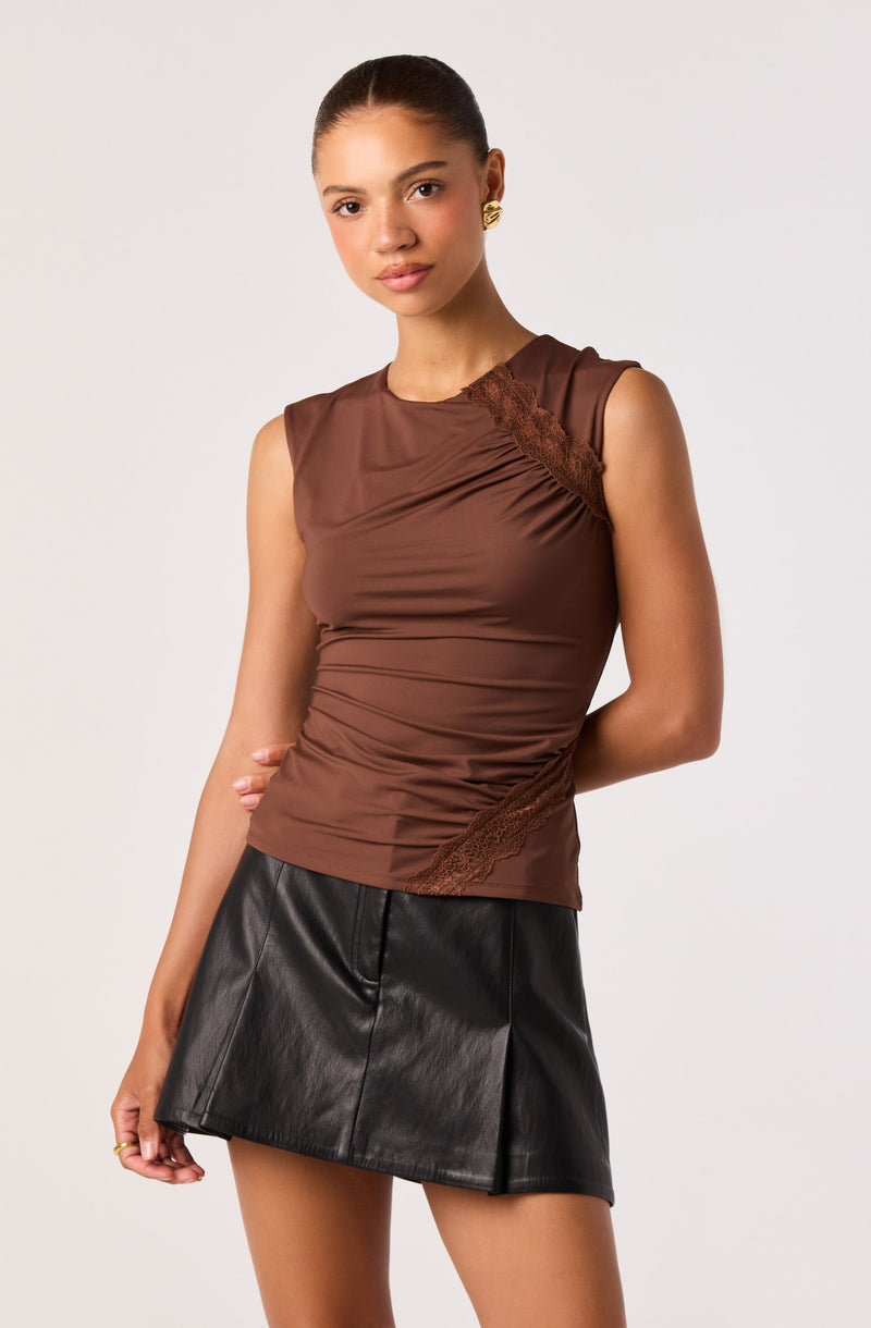 Brown sleeveless top with lace details paired with a black leather mini skirt.