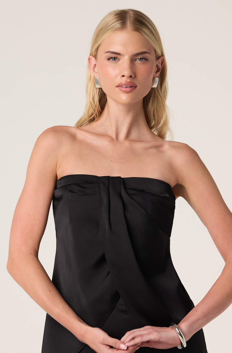 Woman wearing a strapless black satin dress with a pleat in the center.