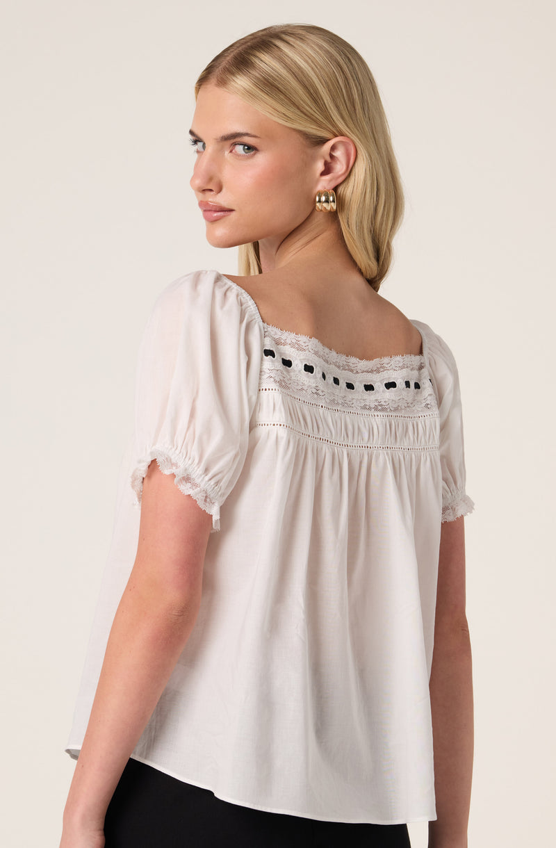 White blouse with puffed sleeves, lace detail, and embroidered accents around the neckline.