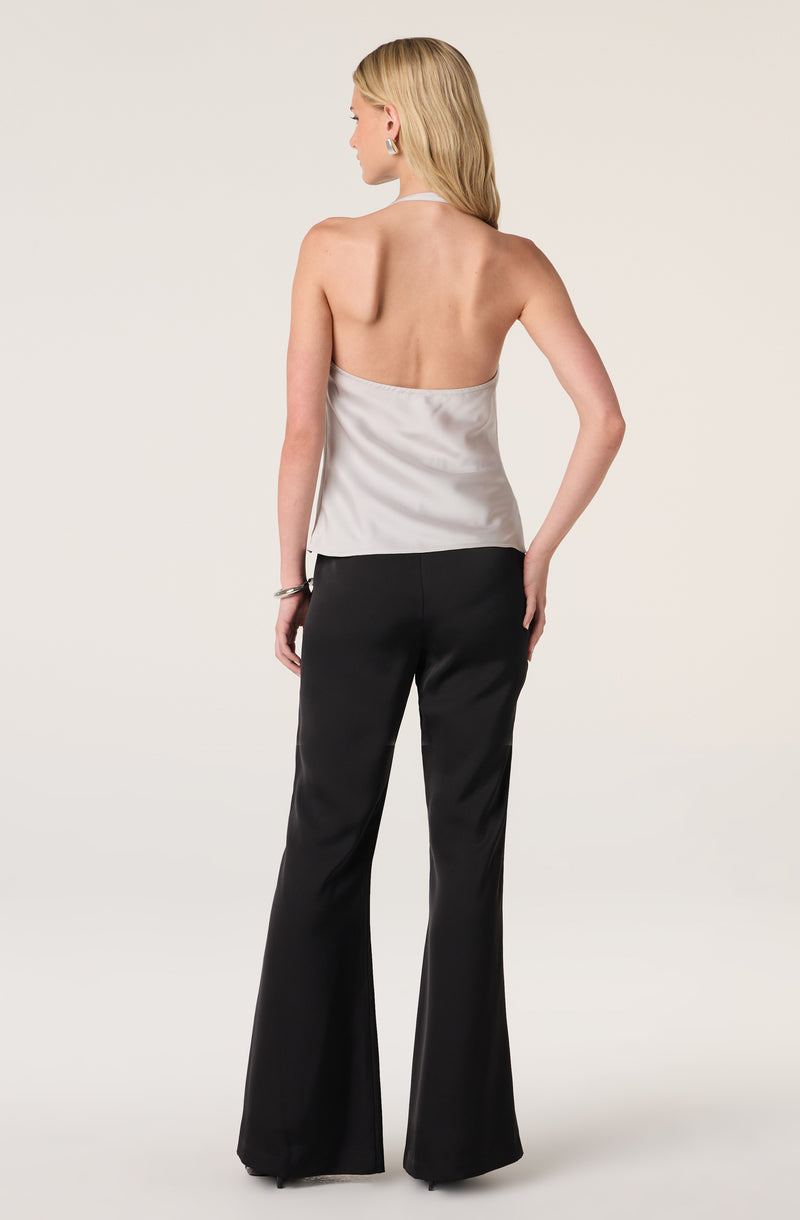 Woman wearing a silver satin halter top and black wide-leg satin pants.