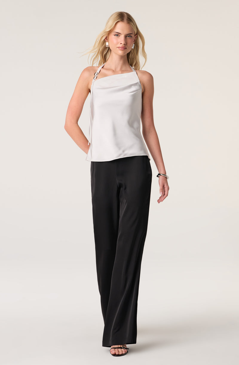 Woman wearing a white satin sleeveless top and black wide-leg satin pants.