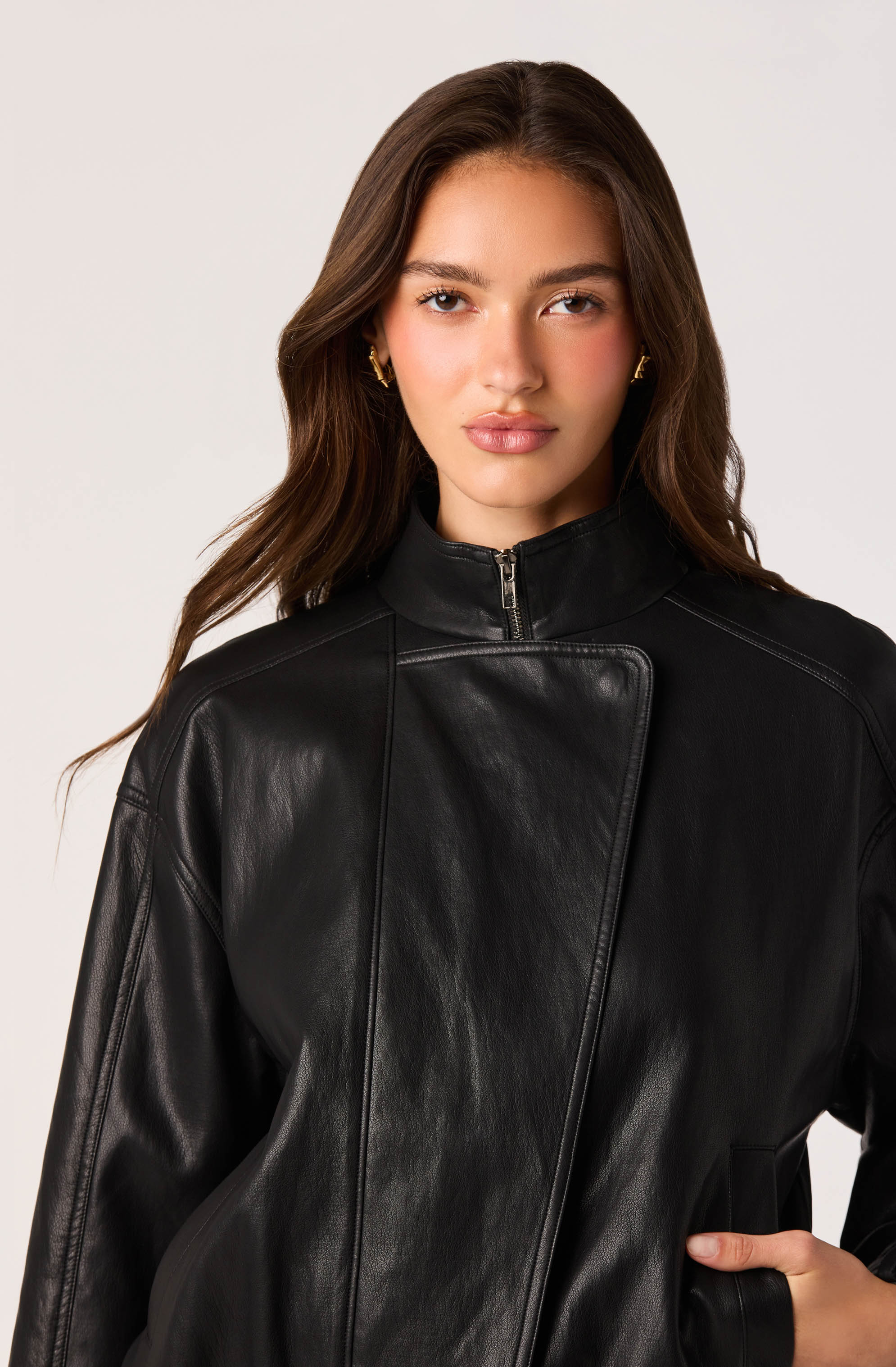 Woman wearing a black leather jacket with a high collar and zipper.
