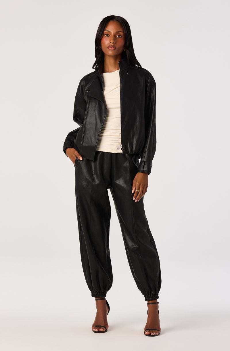 Woman wearing a black leather jacket and matching black leather jogger pants.