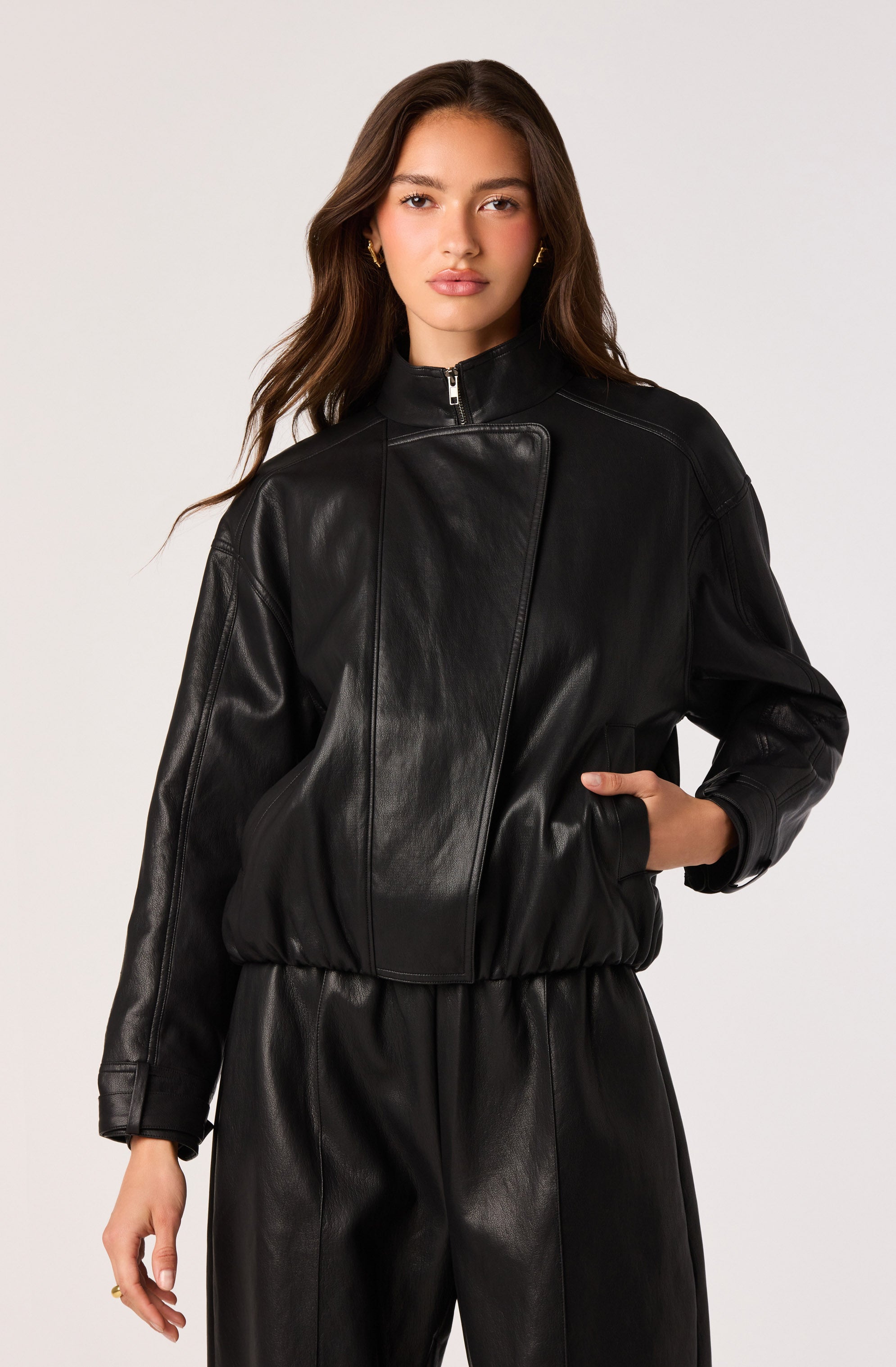 Woman in black leather jacket and matching black leather pants, with a high collar and zip front.