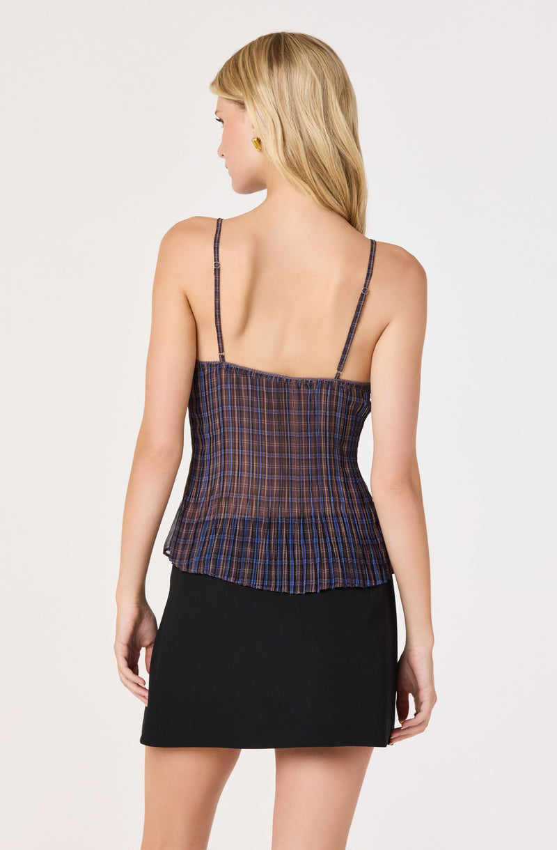 Woman wearing a sleeveless, checkered spaghetti strap top and a black skirt.