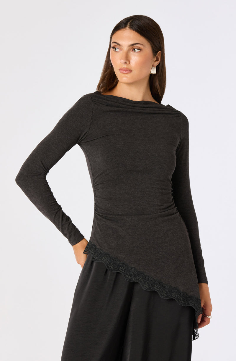 Woman wearing a dark gray long-sleeve top with lace trim at the bottom.