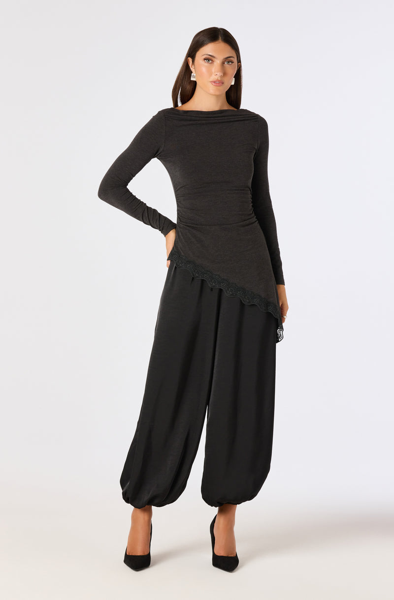 Woman in black long-sleeve top and wide-leg pants with cuffed ankles, wearing black heels.