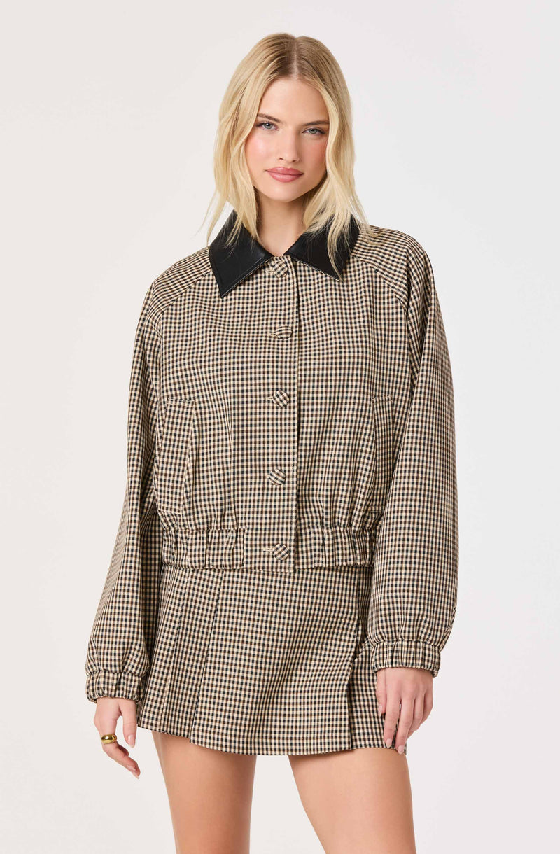 Woman wearing a checkered beige and brown jacket with a black collar and matching checked skirt.
