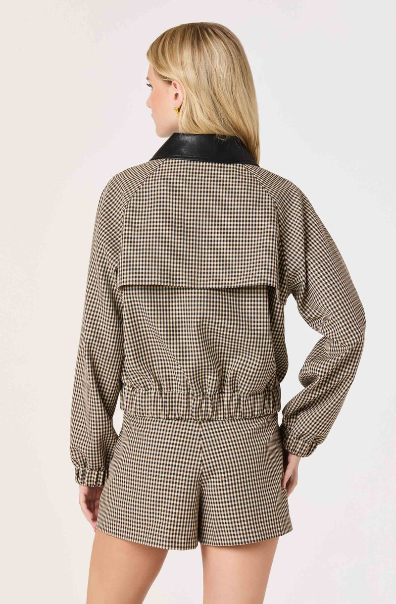 Woman wearing a checkered beige and black jacket with a black collar and matching shorts.