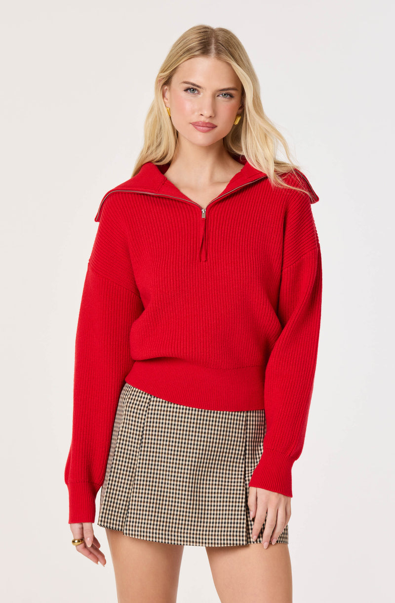 Woman wearing a red zip-up sweater with shoulder epaulets and a checkered mini skirt.