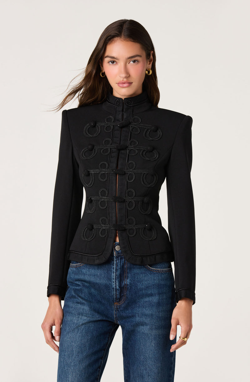 Black military-style jacket with decorative loops and a standing collar, paired with denim jeans.