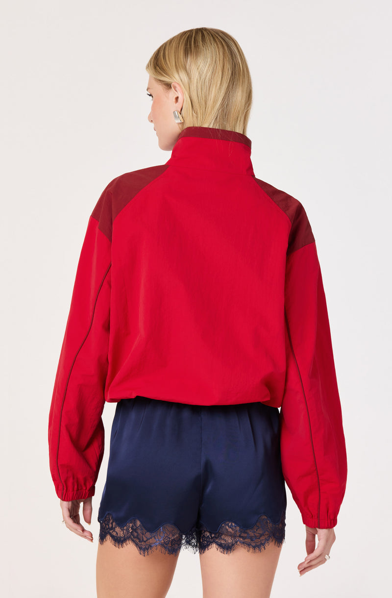 Woman wearing a red and maroon jacket with navy satin shorts with black lace trim.