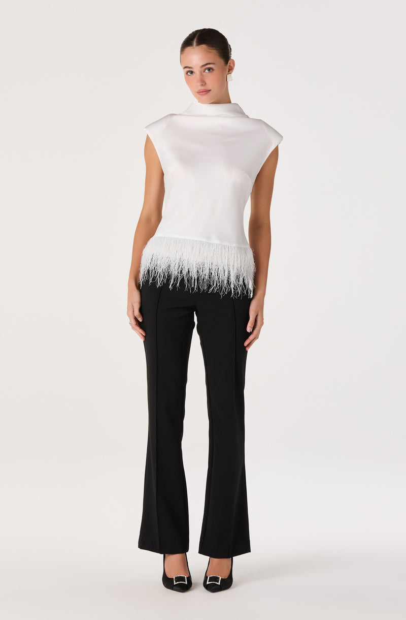 White sleeveless top with feathered hem, paired with black fitted pants.