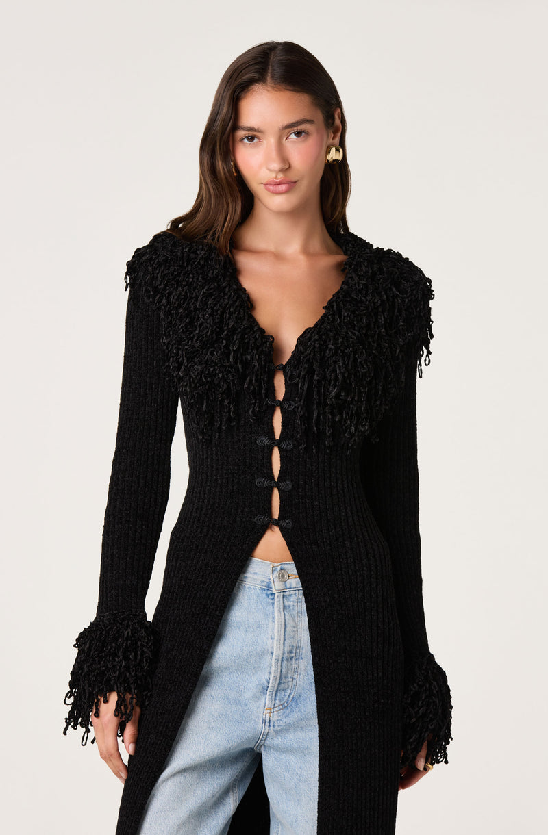 Black long cardigan with textured ruffle details on the shoulders and cuffs, buttoned front.