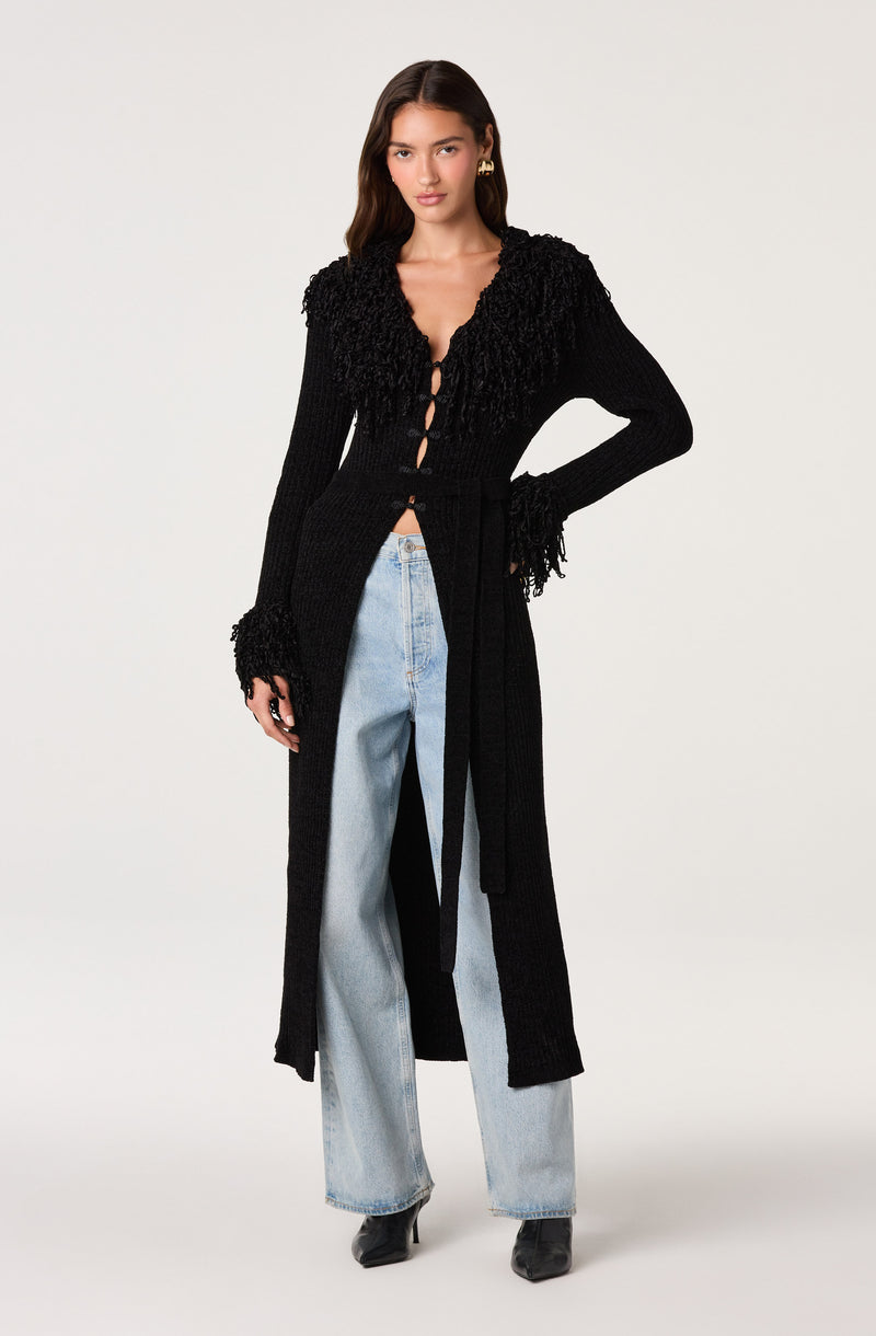 Black long cardigan with textured ruffles on shoulders and sleeves, worn open over a black top and light blue jeans.