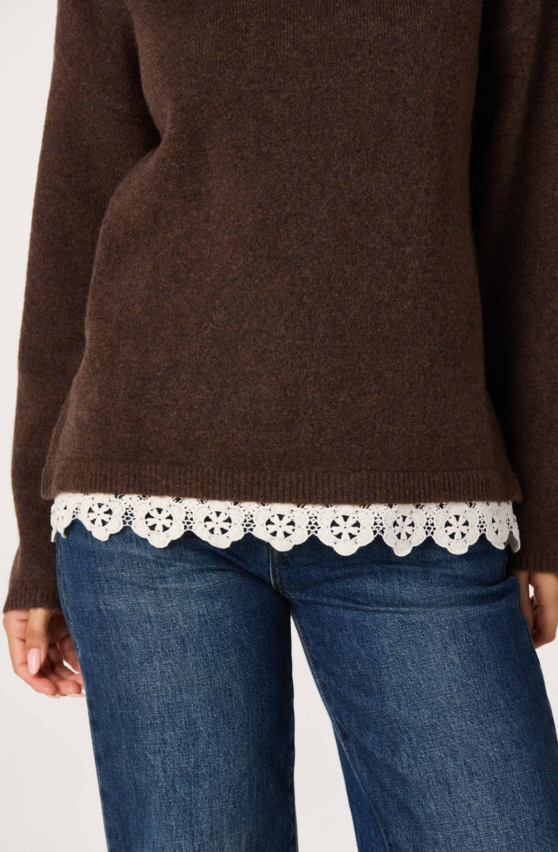 Brown sweater with white lace hem, paired with blue jeans.