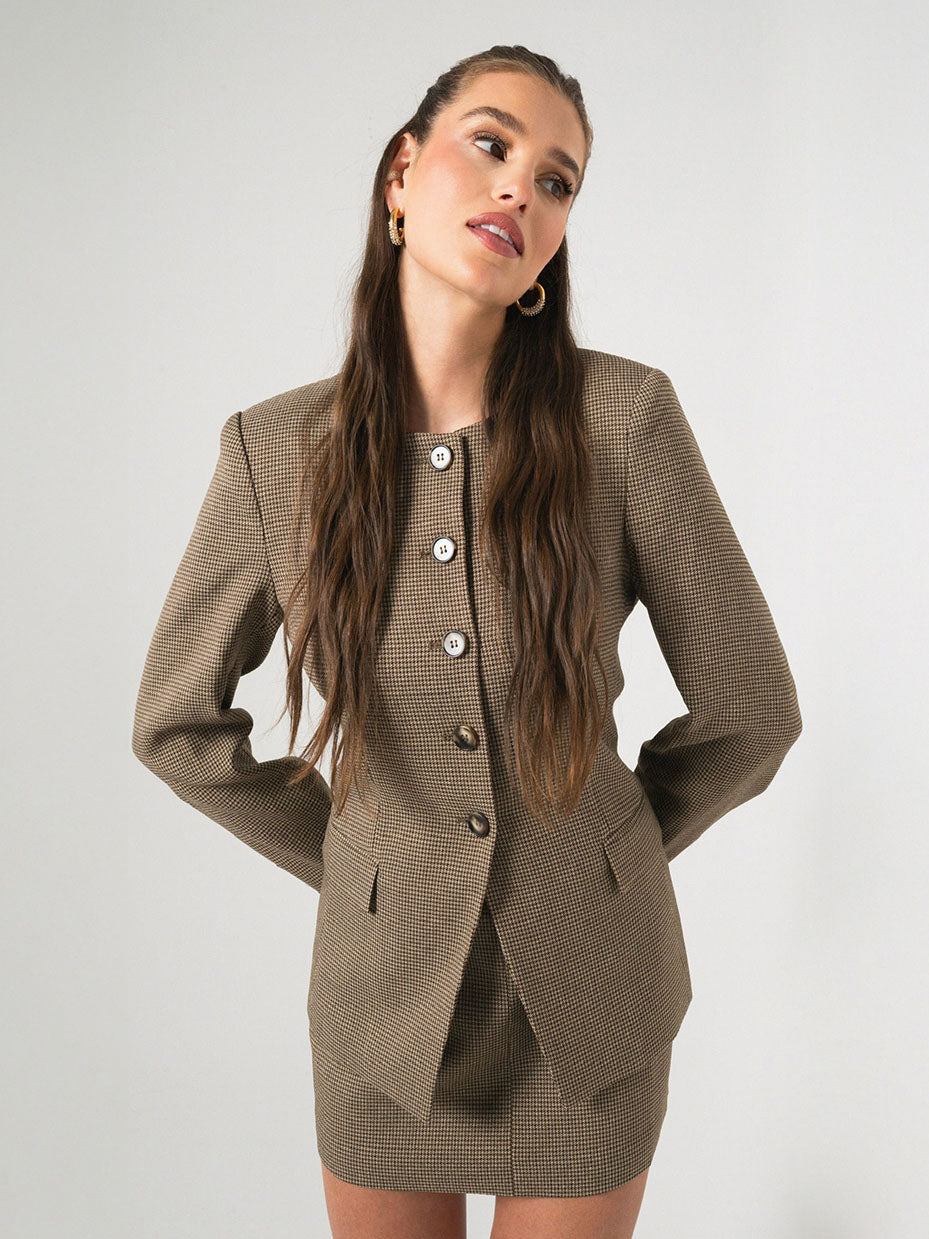 Woman wearing a brown checkered blazer and skirt set against a white background