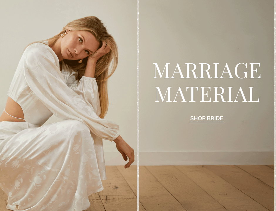 Woman in a silk white dress with long sleeves and floral pattern sitting on the floor.