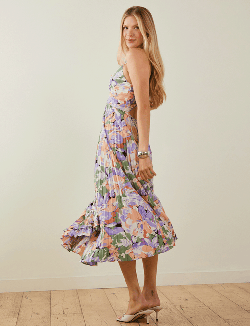 Woman wearing a colorful, floral, sleeveless midi dress with ruffled hem.