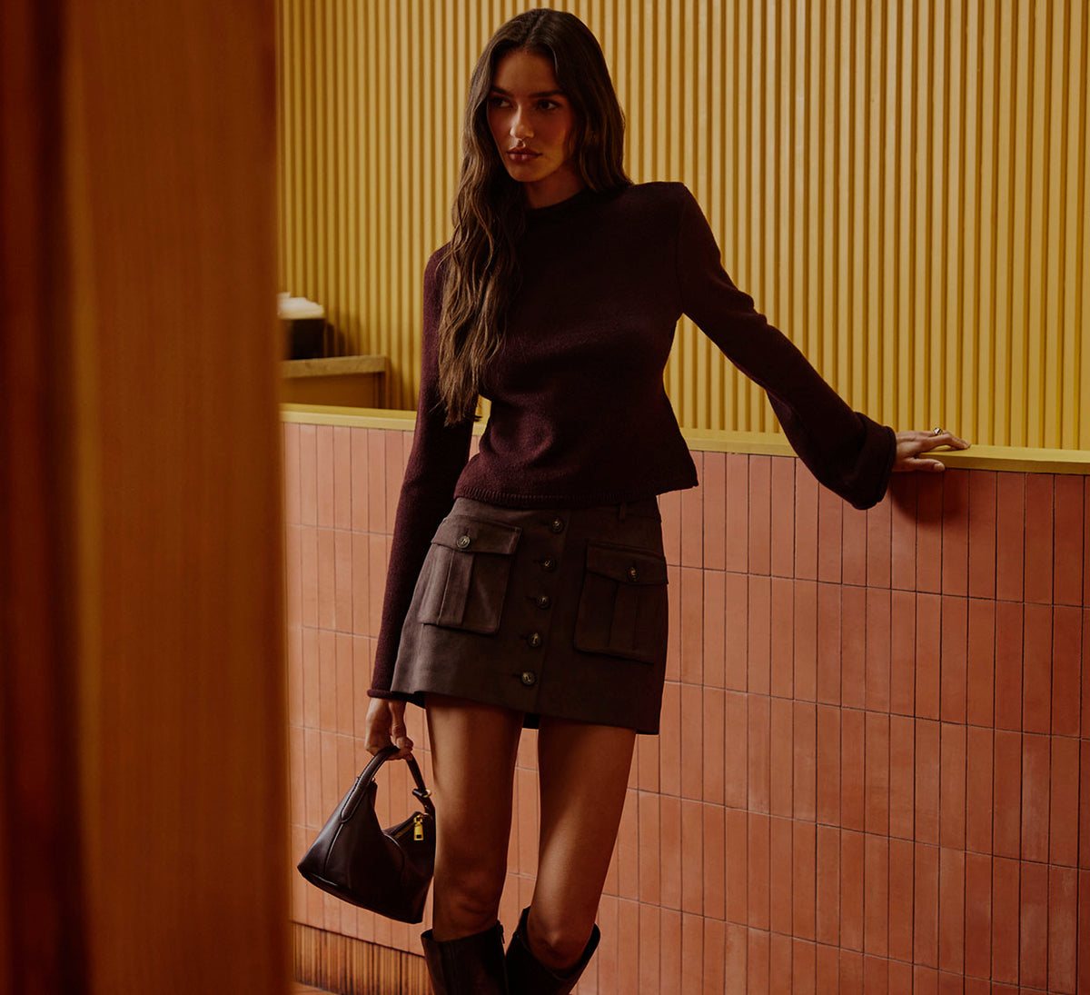 Woman wearing a dark brown long-sleeve sweater and a matching brown button-front skirt.