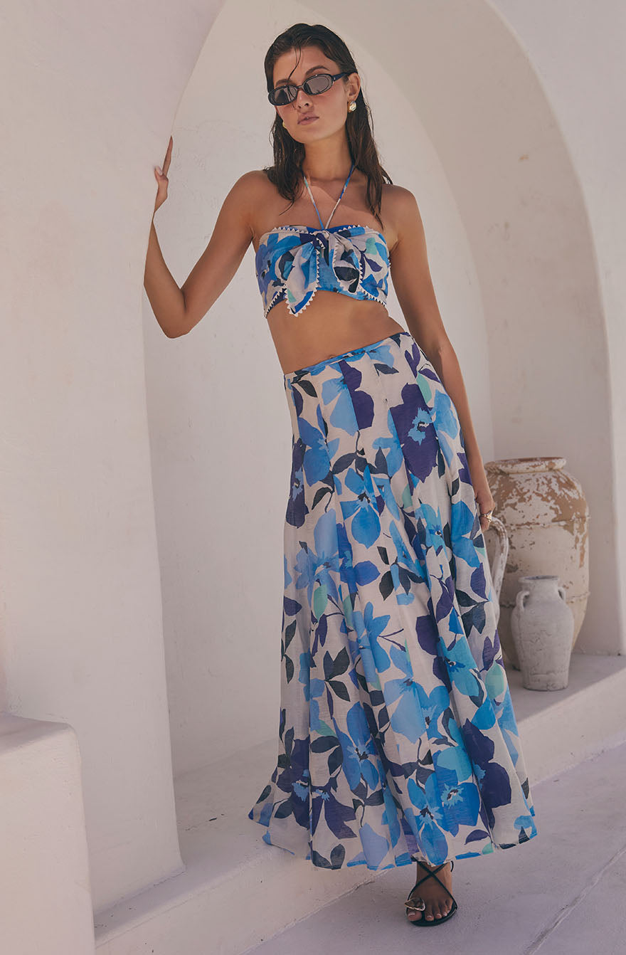 Woman wearing a blue floral strapless crop top and matching long flowy skirt.
