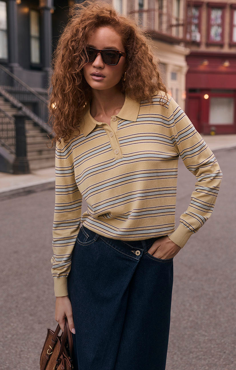 Woman wearing a beige striped long-sleeve polo shirt with buttons.